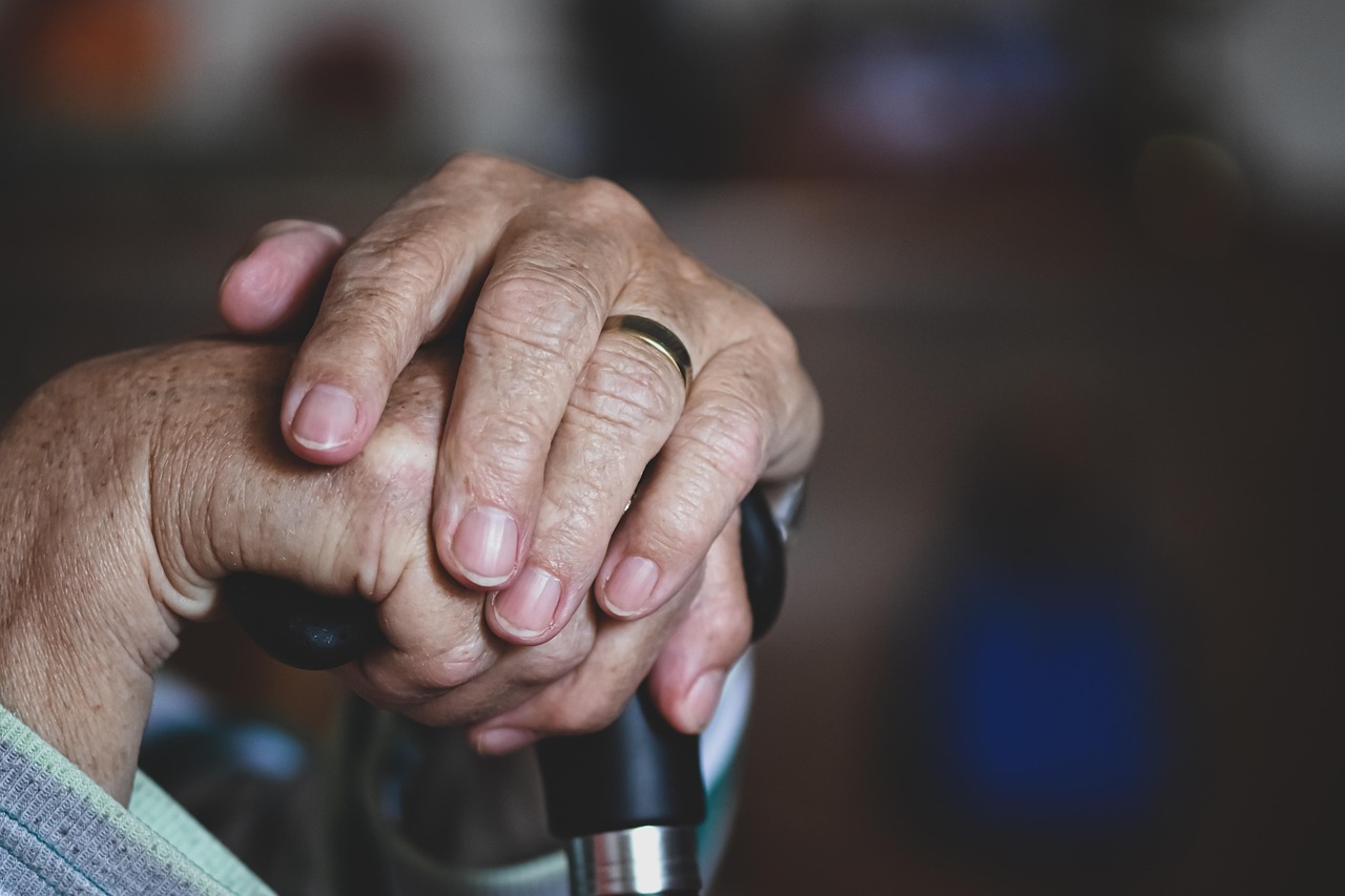 Elderly person's hands holding a walking stick.